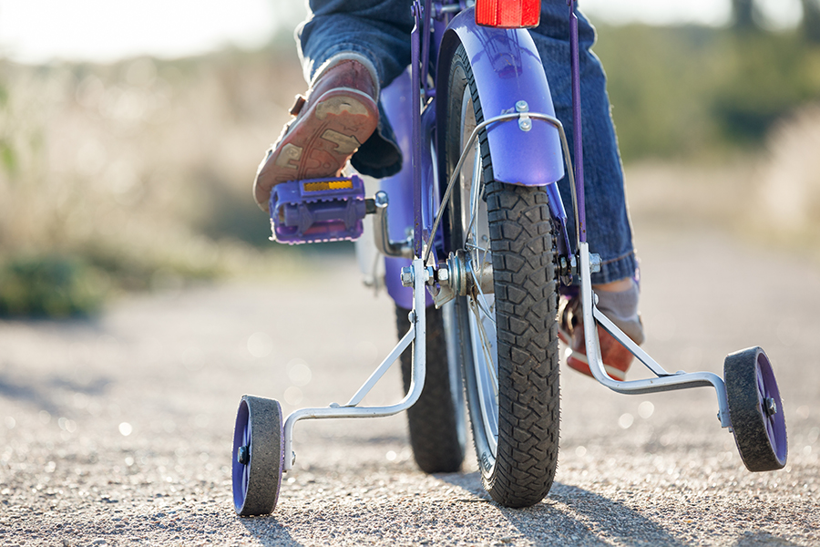 Child riding a bike with training wheels.