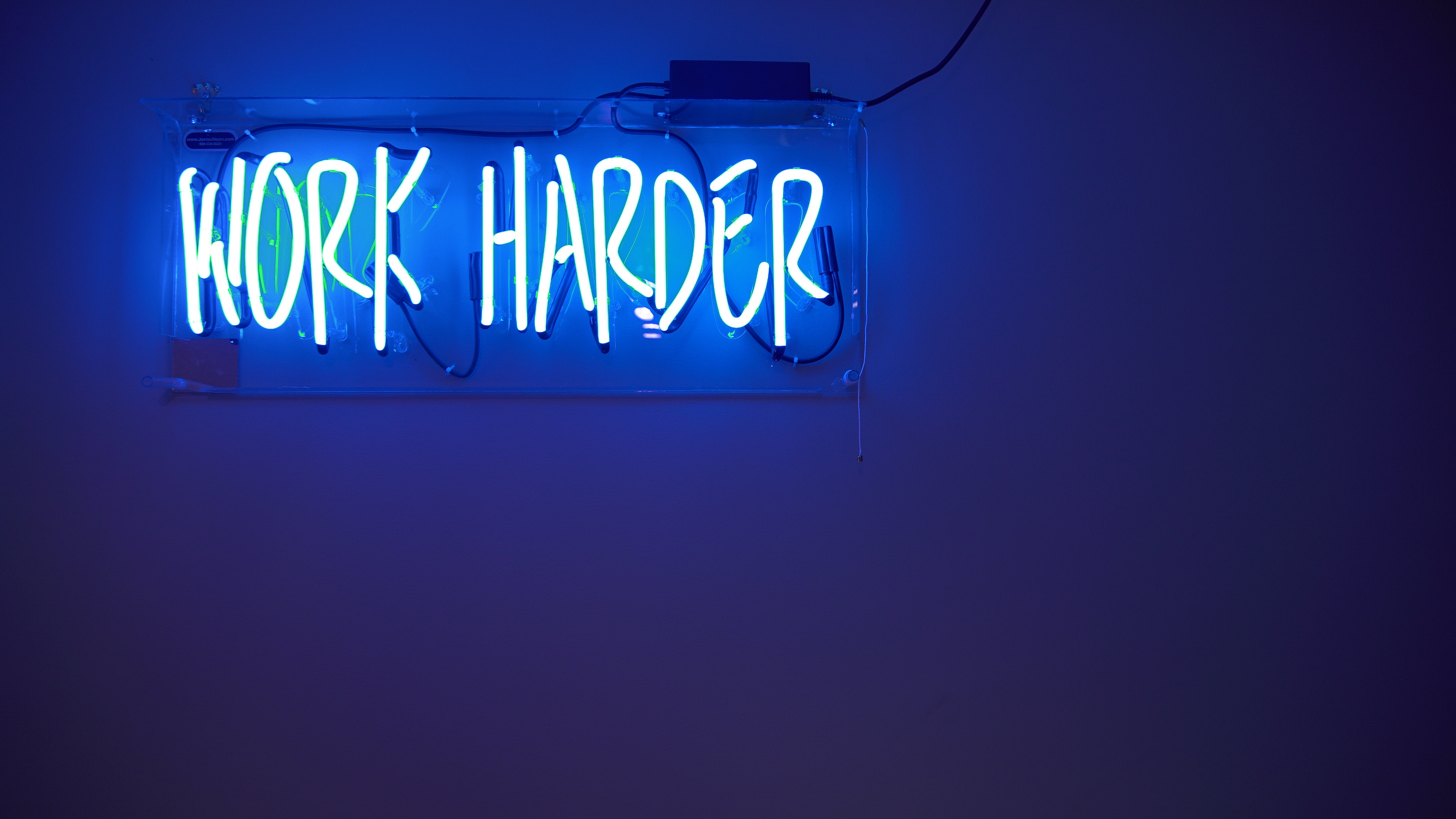 Neon sign reading 'Work Harder' 