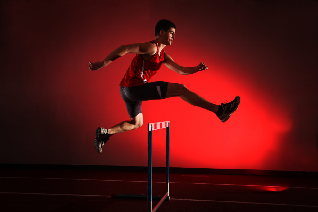 Athlete jumping over a hurdle with the will to improve