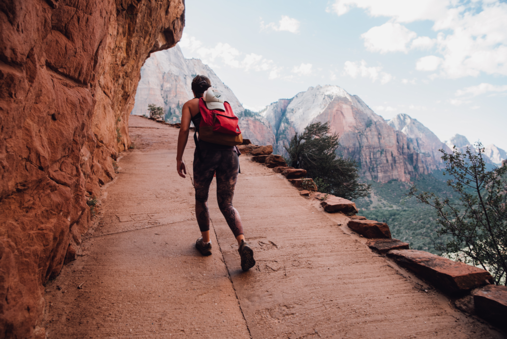 Girl hiking up mountain with backpack.