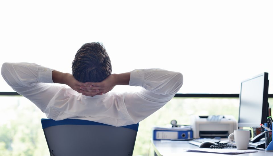 Man leaned back in chair looking out office window.