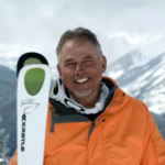 Ski Hall of Fame Member, John Clendenin, in front of mountains with skis.